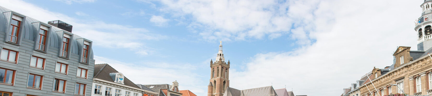 Een sfeervol beeld van het centrum van Roermond, met historische gebouwen en het imposante stadhuis prominent aanwezig op het marktplein.